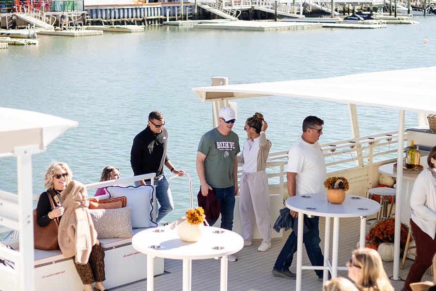 Friends and coworkers chatting around high-top tables on the boat's deck