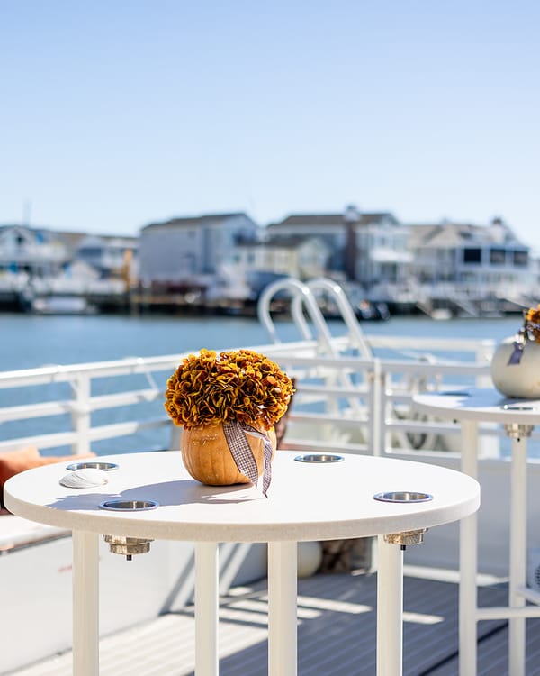A pumpkin centerpiece on a deck table, with waterfront homes across the bay
