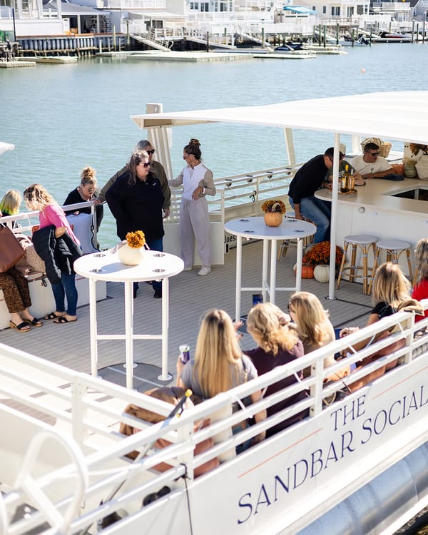 Guests relaxing on the deck of The Sandbar Social at the dock on a sunny fall afternoon