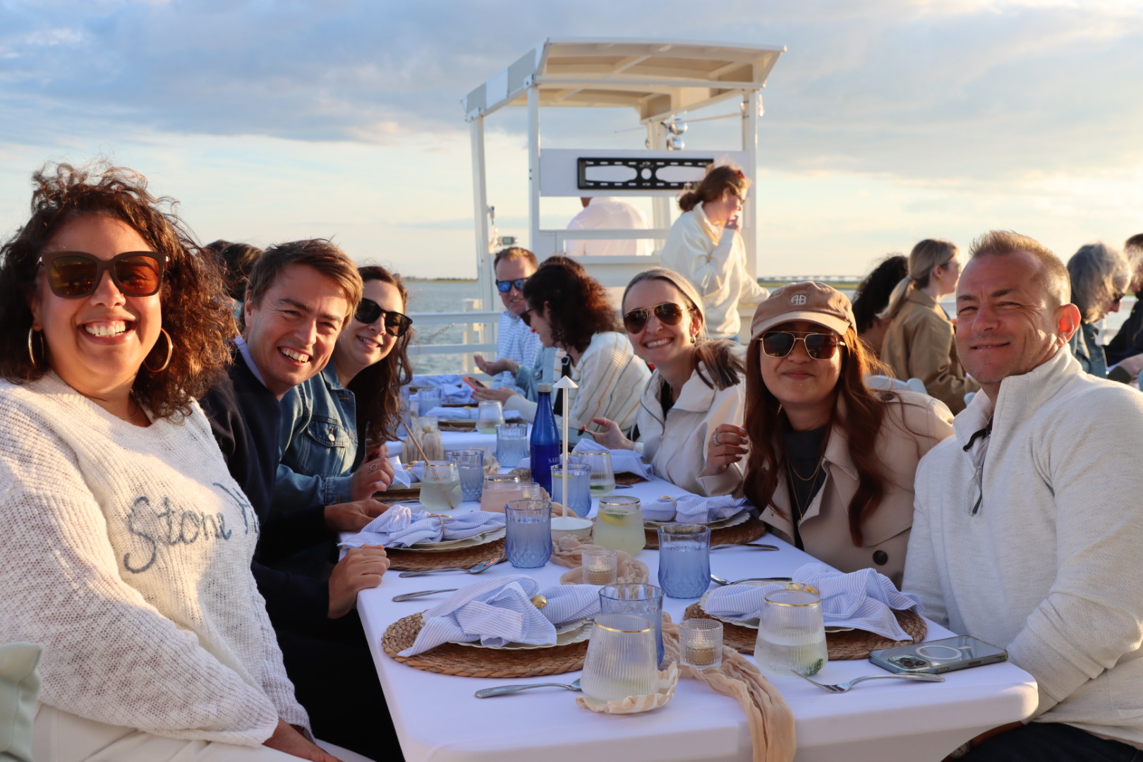 A private group celebrating around a dinner table aboard The Sandbar Social